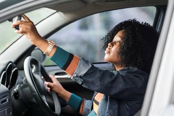 Woman in car checking mirror