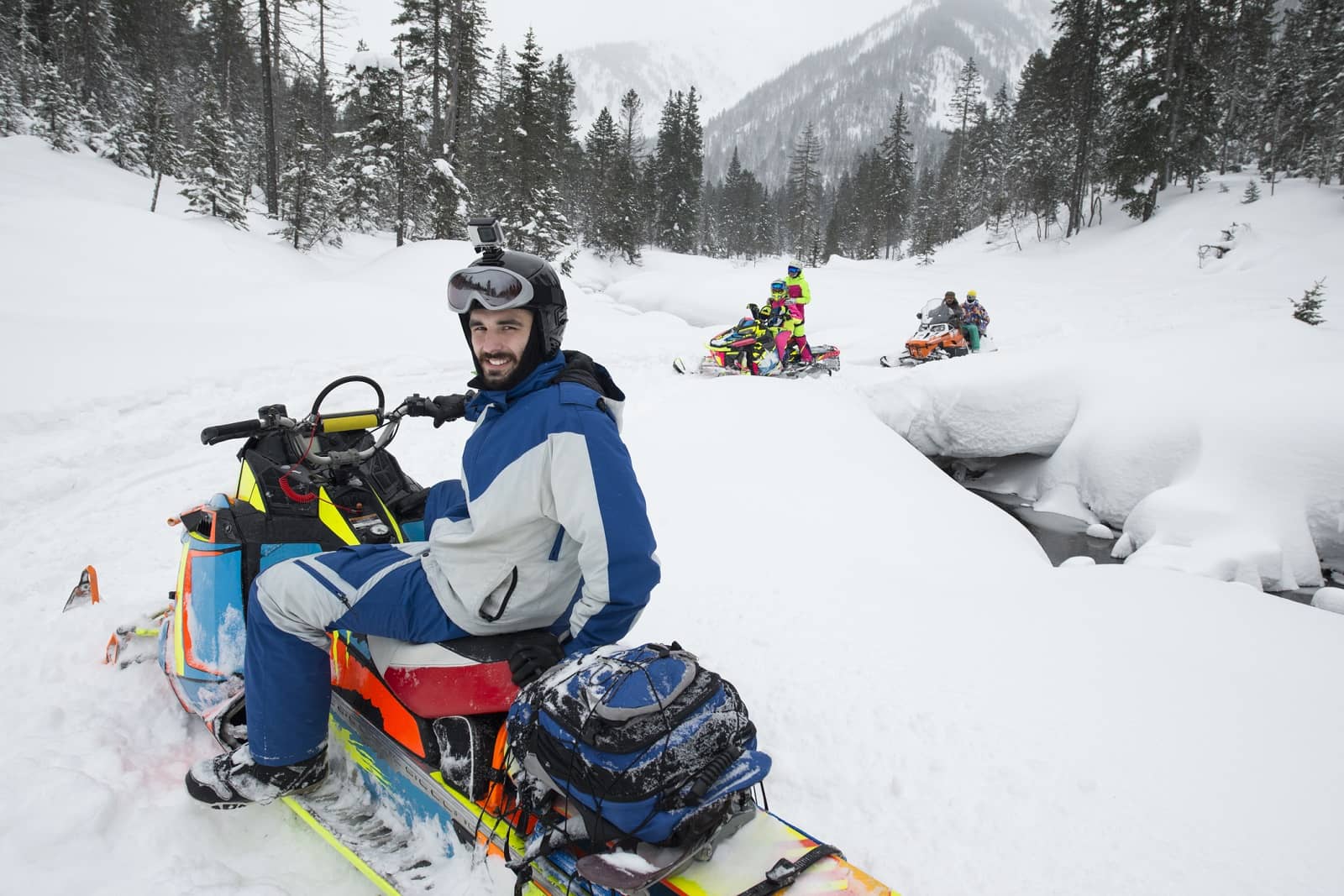 Snowmobilers riding through forest