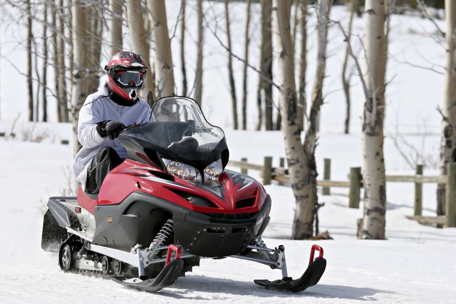 Person driving red and black snowmobile
